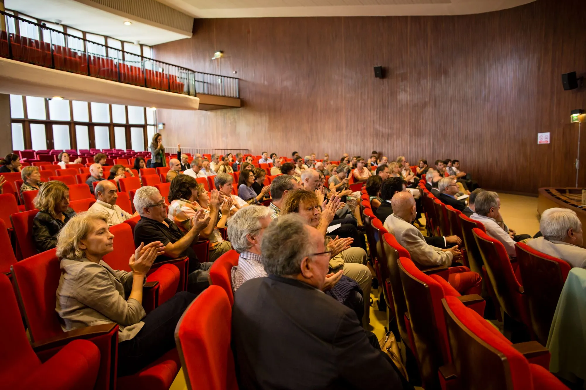 Salle comble écoutant les intervenants, vue depuis les gradins