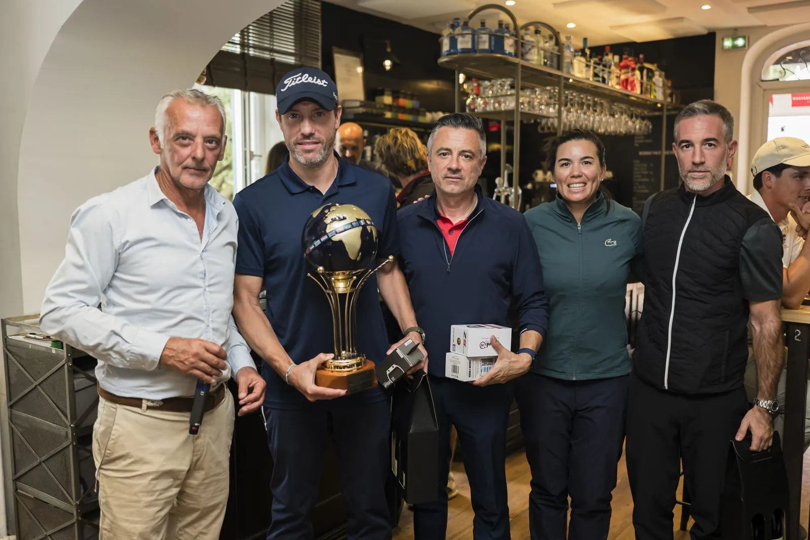 Lauréats posant avec le trophée devant le bar du club house