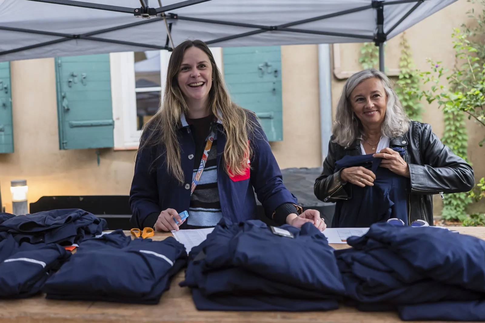 Deux hôtesses souriantes derrière une table de polos pliés