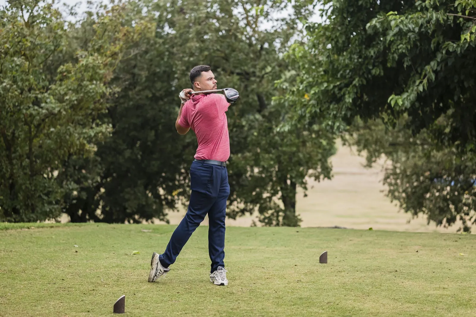 Joueur en polo rouge en fin de mouvement, le regard suivant la balle