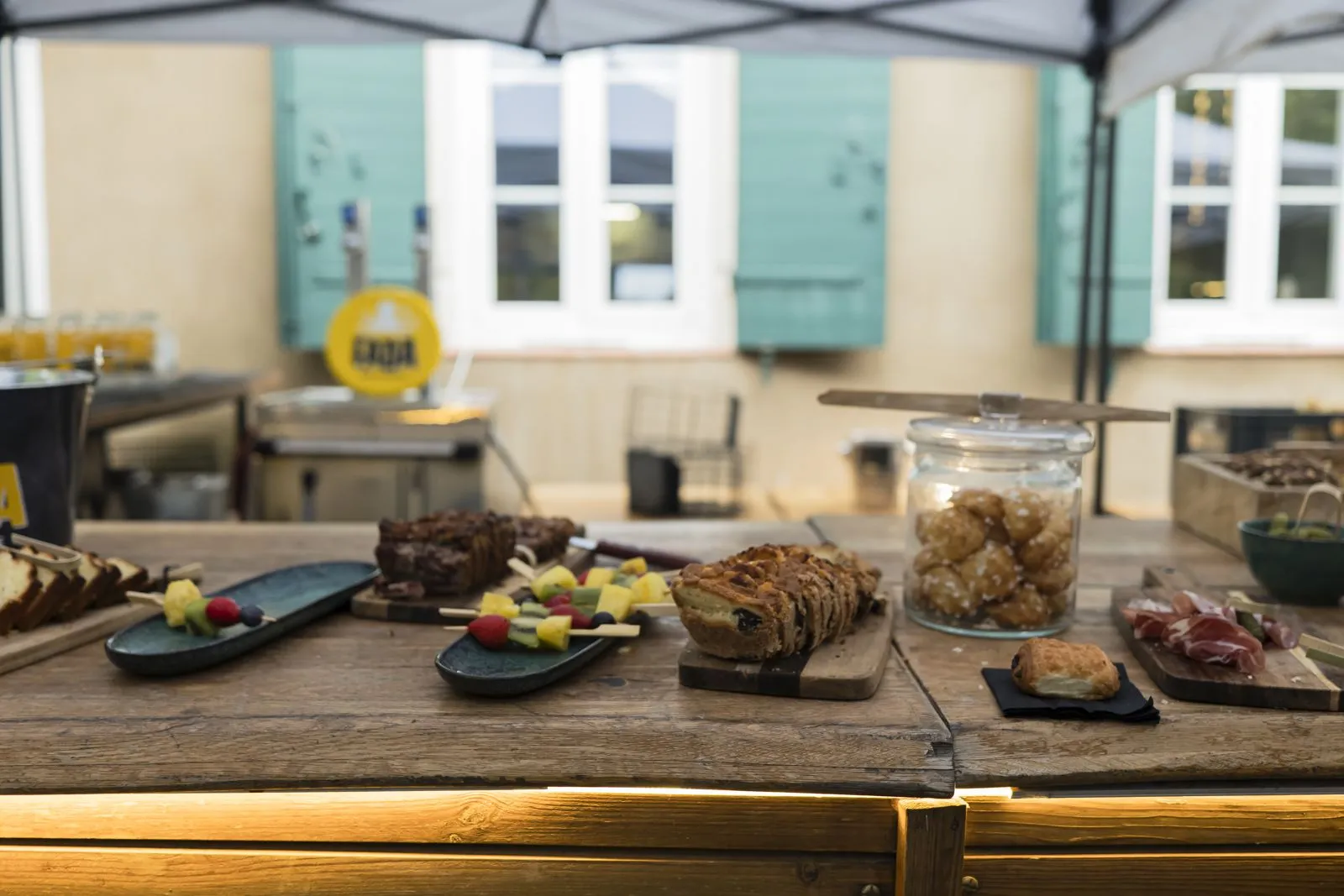 Buffet de cakes, brochettes de fruits et chouquettes sur une table en bois