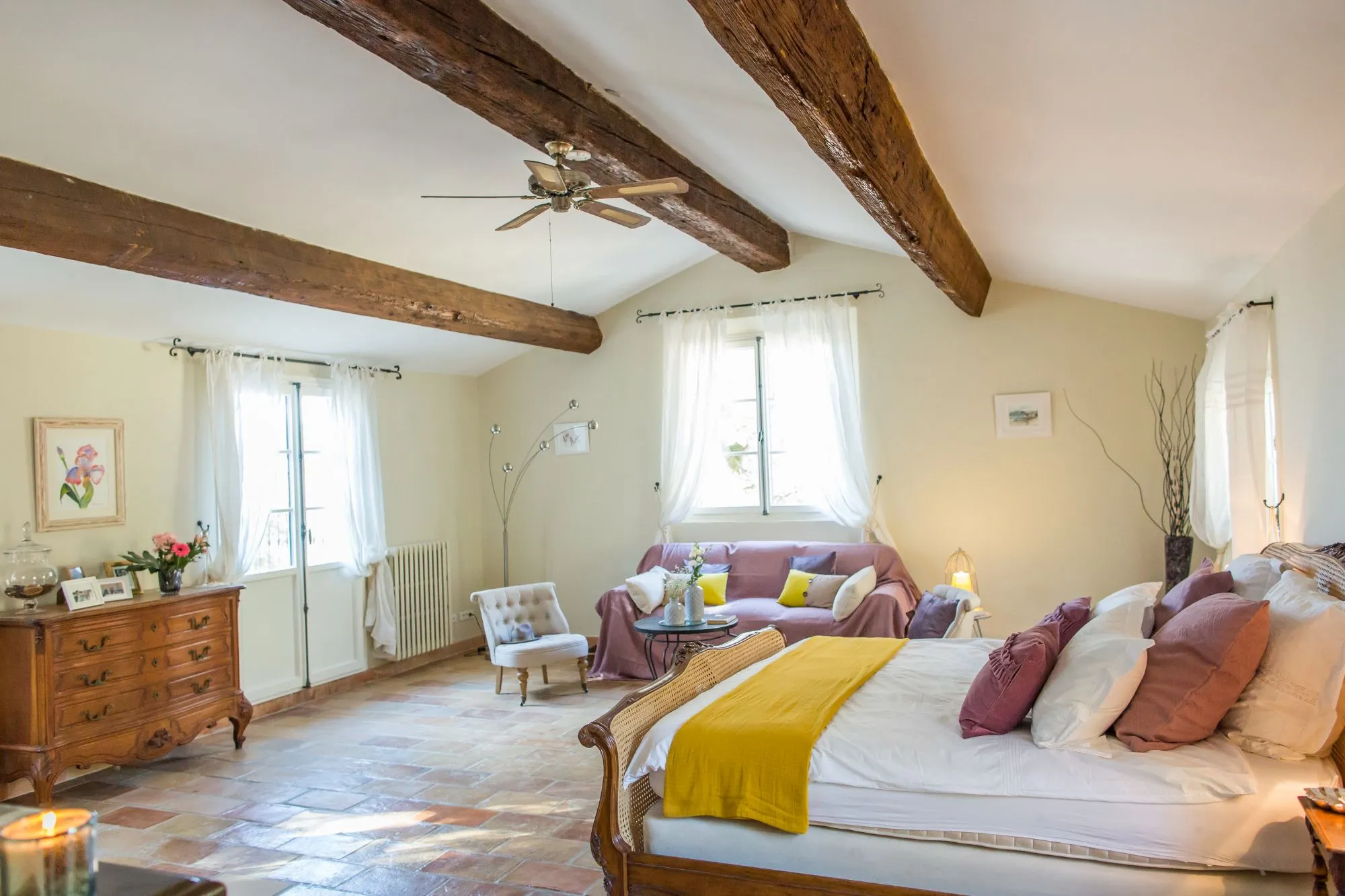 Chambre lumineuse avec lit et fauteuils sous poutres