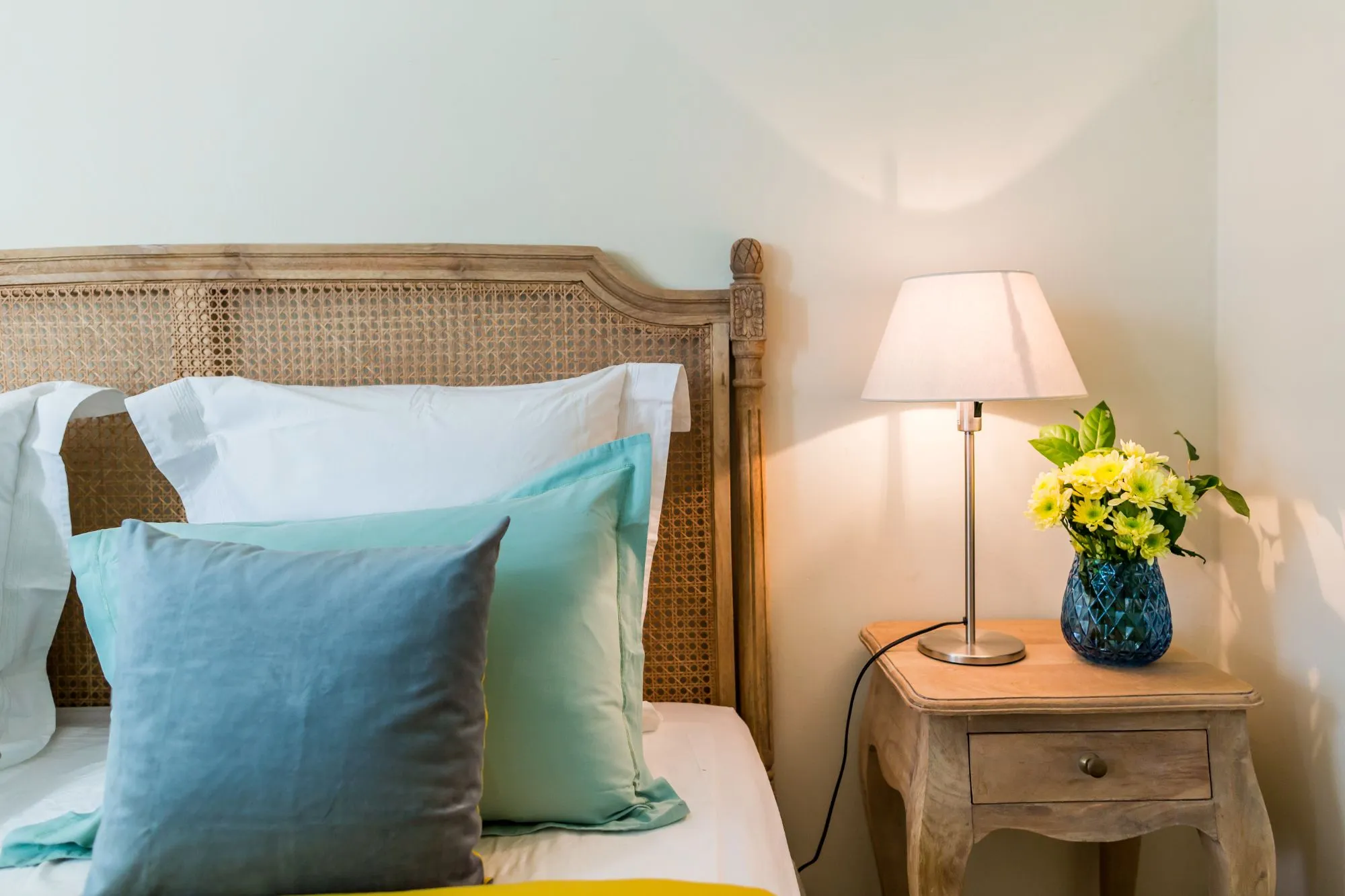 Détail d'un lit, coussins bleus et lampe de chevet