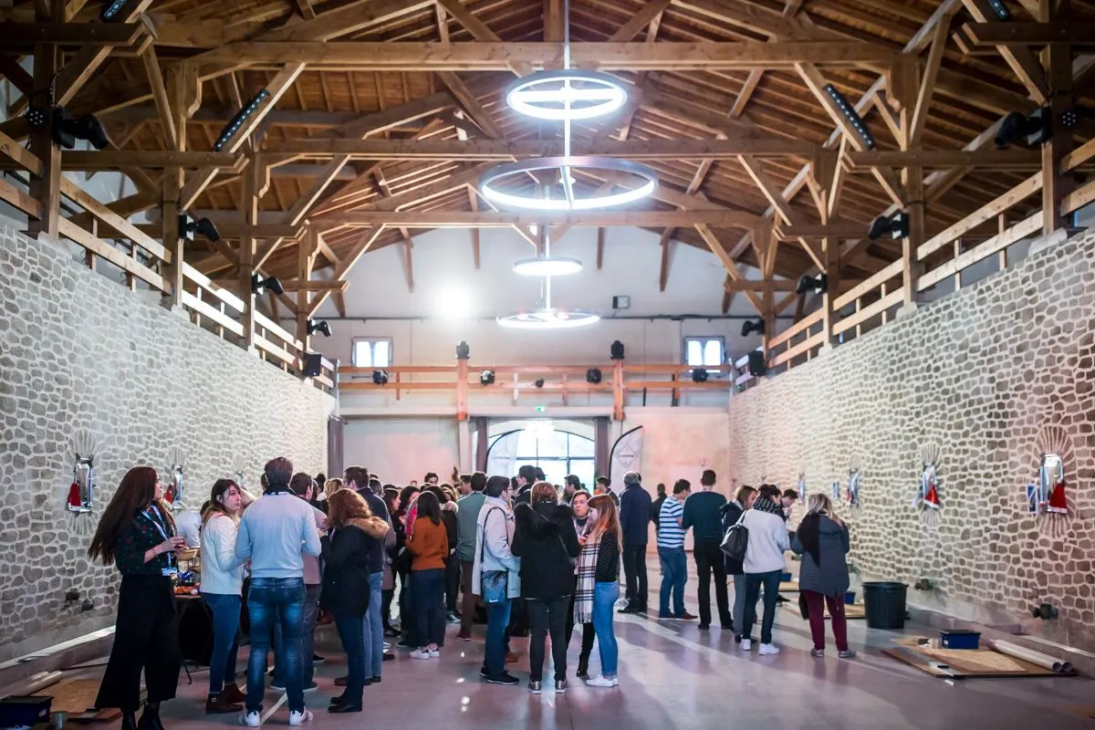 Groupe rassemblé sous la charpente d'une grande salle en pierre