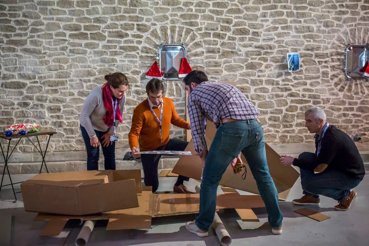 Équipe construisant un objet en carton près d'un mur en pierre